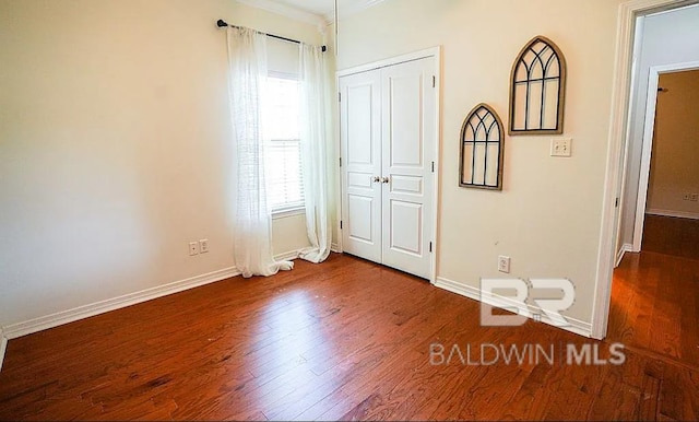 unfurnished bedroom featuring ornamental molding and dark hardwood / wood-style floors