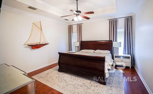 bedroom with a tray ceiling, ornamental molding, hardwood / wood-style floors, and ceiling fan