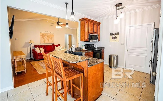 kitchen featuring crown molding, black electric range oven, sink, and decorative light fixtures