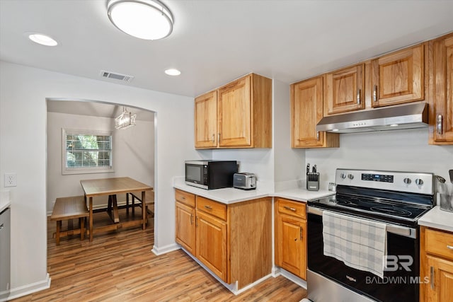 kitchen featuring a notable chandelier, stainless steel appliances, and light hardwood / wood-style flooring