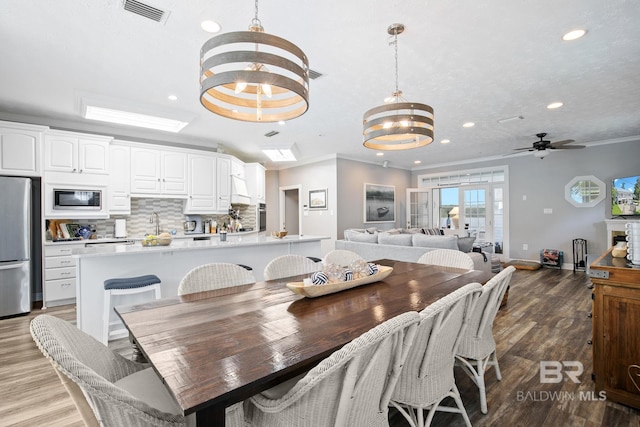 dining space featuring ceiling fan with notable chandelier, wood-type flooring, and crown molding