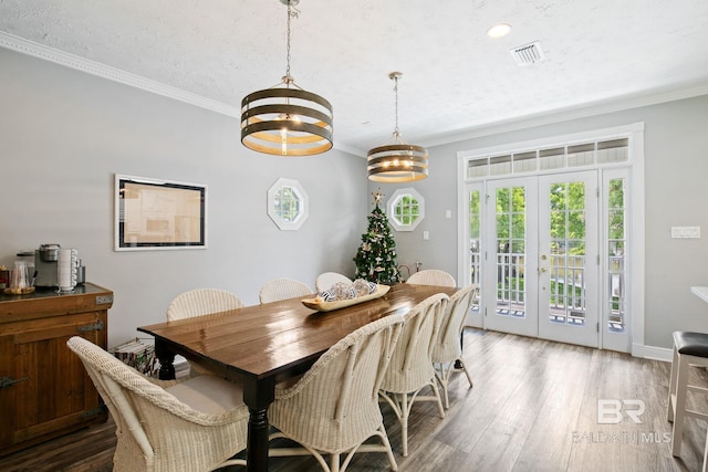 dining space featuring french doors, ornamental molding, a textured ceiling, a notable chandelier, and hardwood / wood-style floors