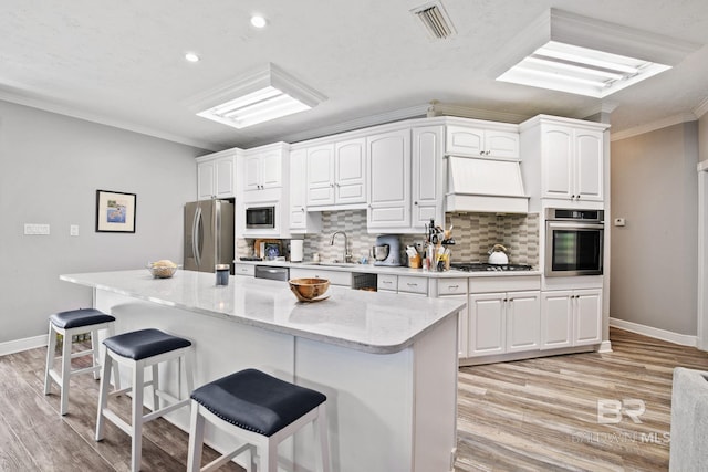 kitchen featuring premium range hood, white cabinetry, stainless steel appliances, and ornamental molding