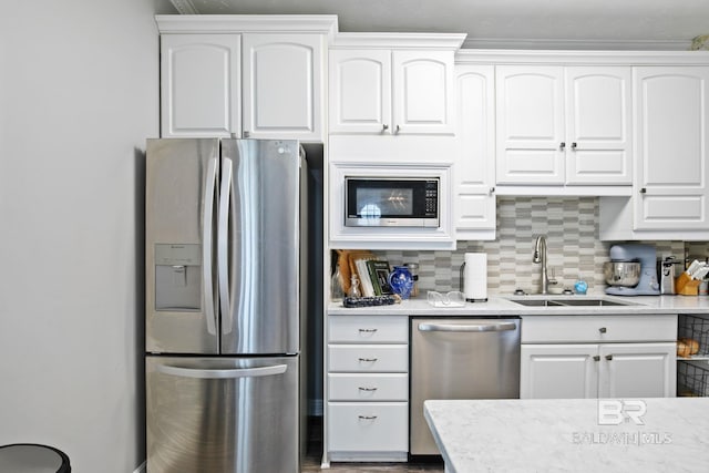 kitchen with backsplash, sink, white cabinets, and stainless steel appliances