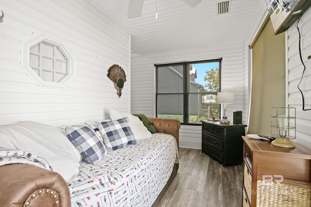 bedroom with wood walls, vaulted ceiling, dark wood-type flooring, and a closet