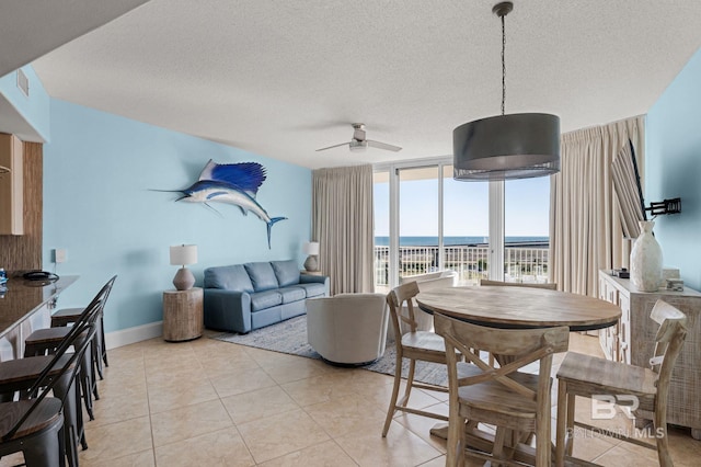 28103 Perdido Beach Blvd Unit B 516, Orange Beach, AL 36561 - dining room featuring a water view, a ceiling fan, a textured ceiling, a wall of windows, and light tile patterned flooring