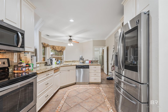 kitchen with kitchen peninsula, appliances with stainless steel finishes, light stone counters, sink, and white cabinetry