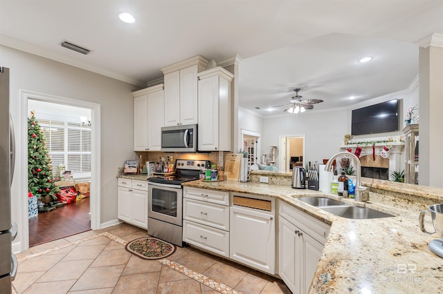 kitchen with sink, ceiling fan, ornamental molding, white cabinetry, and stainless steel appliances