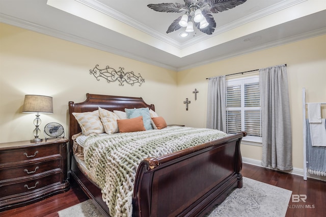 bedroom with dark hardwood / wood-style floors, ceiling fan, ornamental molding, and a tray ceiling