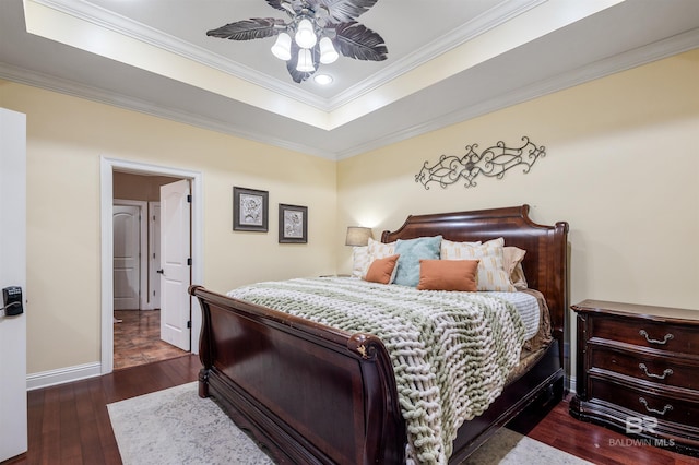 bedroom with a tray ceiling, crown molding, ceiling fan, and dark wood-type flooring