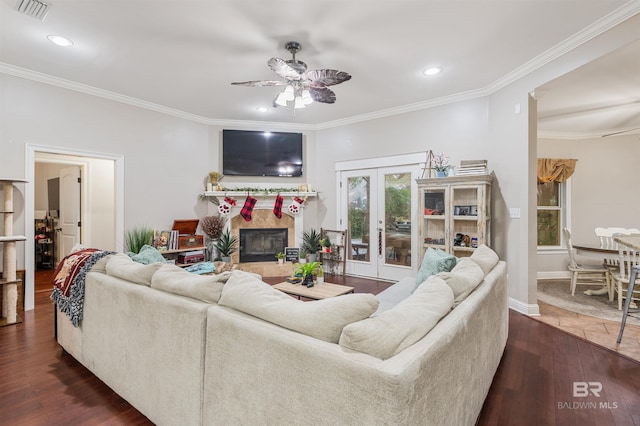 living room featuring french doors, dark hardwood / wood-style floors, ceiling fan, ornamental molding, and a tiled fireplace