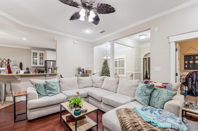 living room with ceiling fan with notable chandelier, dark hardwood / wood-style flooring, ornate columns, and crown molding