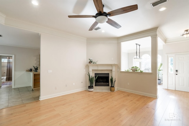 unfurnished living room with crown molding, a fireplace, light hardwood / wood-style floors, and ceiling fan