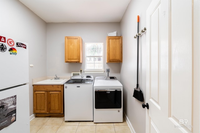 clothes washing area with washer and clothes dryer, cabinets, sink, and light tile patterned flooring