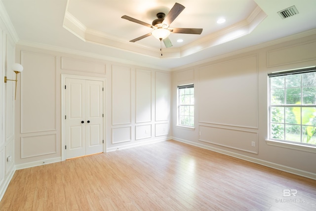 unfurnished bedroom with ceiling fan, light wood-type flooring, crown molding, and a tray ceiling