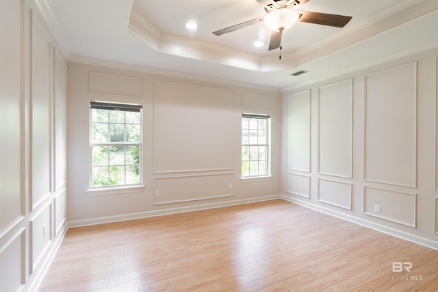 empty room featuring ornamental molding, light hardwood / wood-style floors, and a raised ceiling