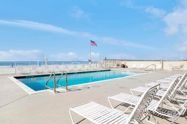 view of swimming pool with a water view and a patio area