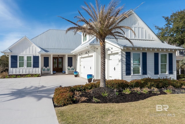 modern inspired farmhouse featuring board and batten siding, metal roof, driveway, and an attached garage