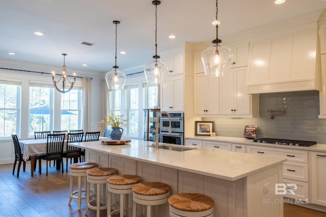 kitchen featuring cooktop, light wood-style flooring, backsplash, stainless steel double oven, and a sink