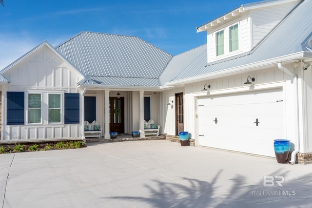 modern farmhouse with covered porch, metal roof, board and batten siding, and driveway