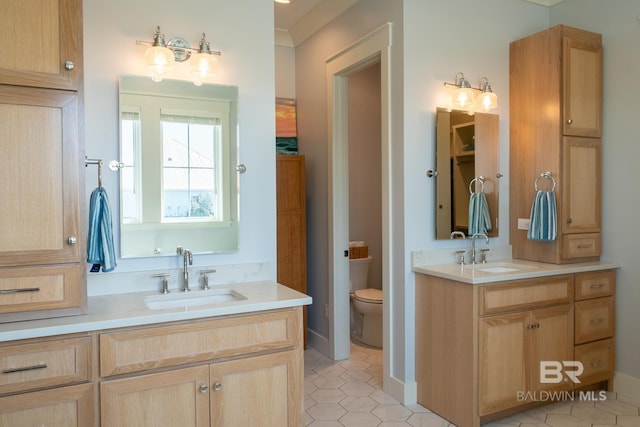 bathroom with toilet, two vanities, a sink, and tile patterned floors