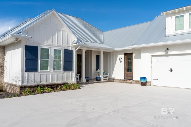 modern farmhouse style home featuring driveway, an attached garage, metal roof, and board and batten siding