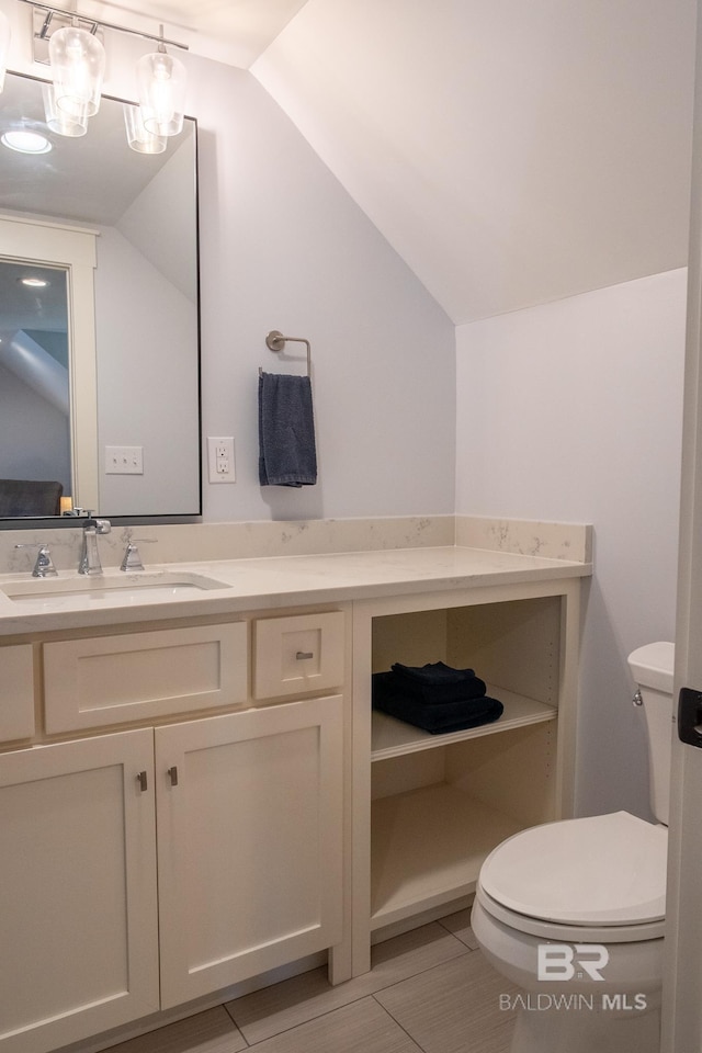 bathroom with toilet, vaulted ceiling, and vanity