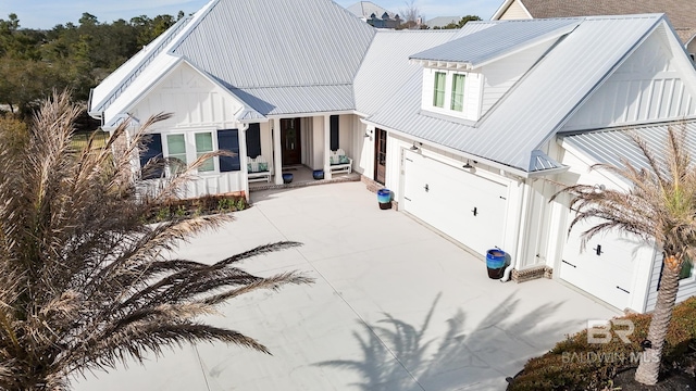 modern farmhouse style home featuring a garage, metal roof, board and batten siding, and concrete driveway