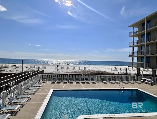 view of swimming pool featuring a water view and a view of the beach