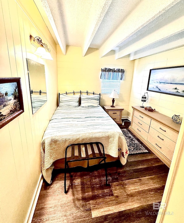 bedroom with beam ceiling, a textured ceiling, and dark hardwood / wood-style floors