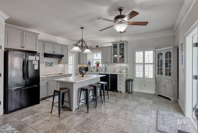 4209 Antigua Ct, Orange Beach, AL 36561 - kitchen featuring light countertops, under cabinet range hood, a sink, a breakfast bar area, and black appliances