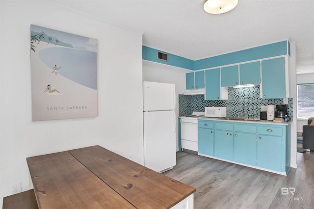 325 E 22nd Ave Unit 8, Gulf Shores, AL 36542 - kitchen with white appliances, blue cabinetry, a sink, and light wood-type flooring