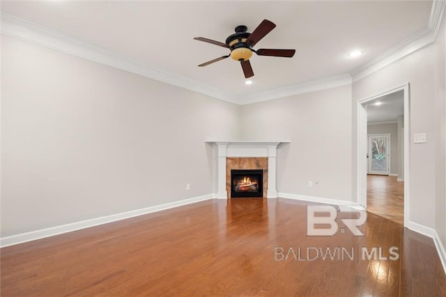 unfurnished living room featuring a tile fireplace, crown molding, ceiling fan, and dark hardwood / wood-style flooring