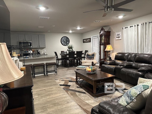 living room with a ceiling fan, light wood-type flooring, visible vents, and recessed lighting