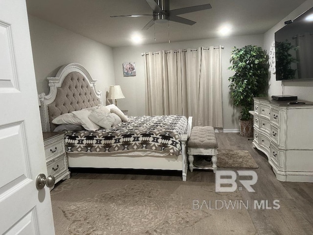 bedroom featuring baseboards, dark wood finished floors, and a ceiling fan