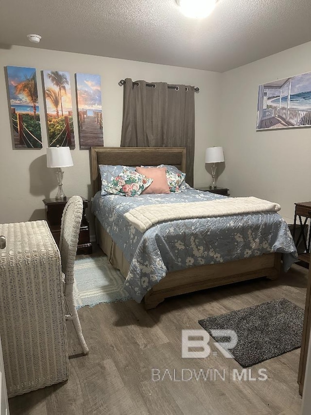 bedroom with a textured ceiling and wood finished floors