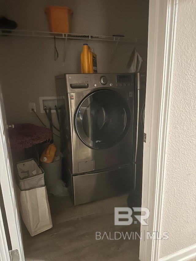 clothes washing area with laundry area, washer / clothes dryer, and wood finished floors