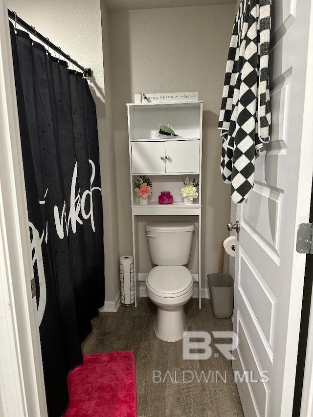 bathroom with wood finished floors, toilet, and baseboards