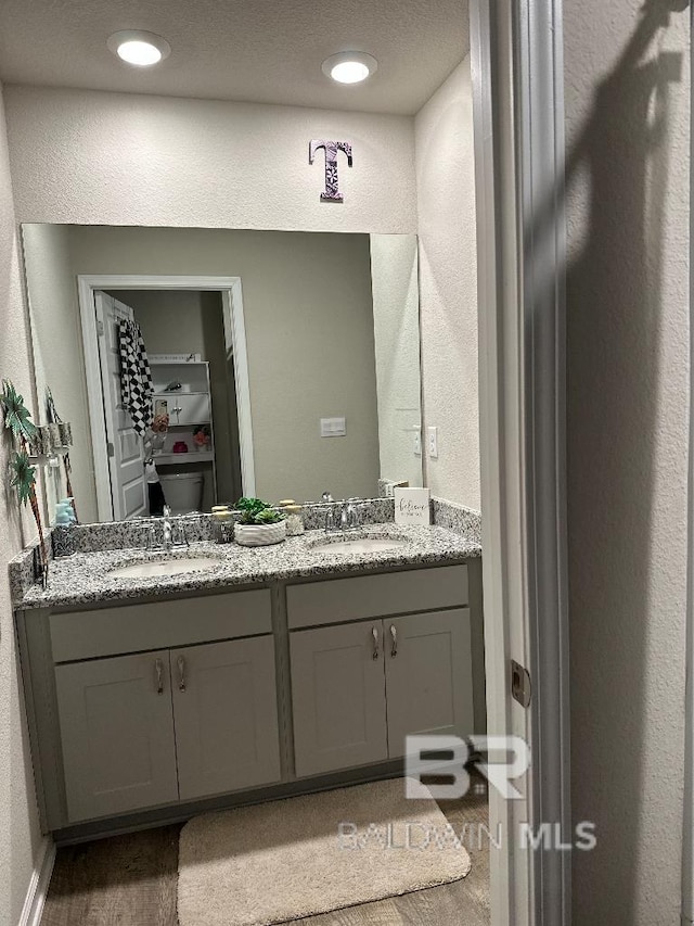 bathroom with a textured wall, double vanity, and a sink