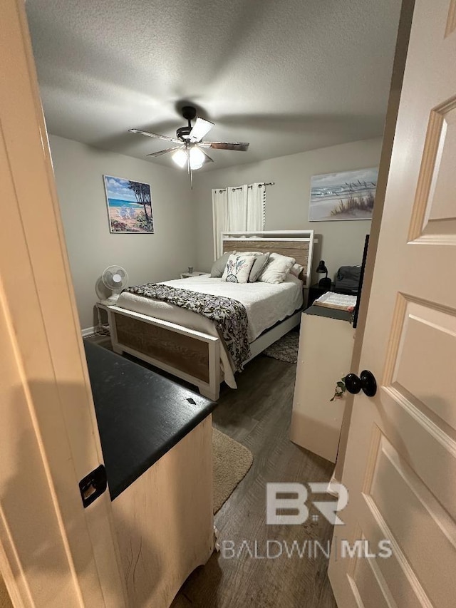 bedroom featuring a textured ceiling, dark wood-style flooring, and a ceiling fan