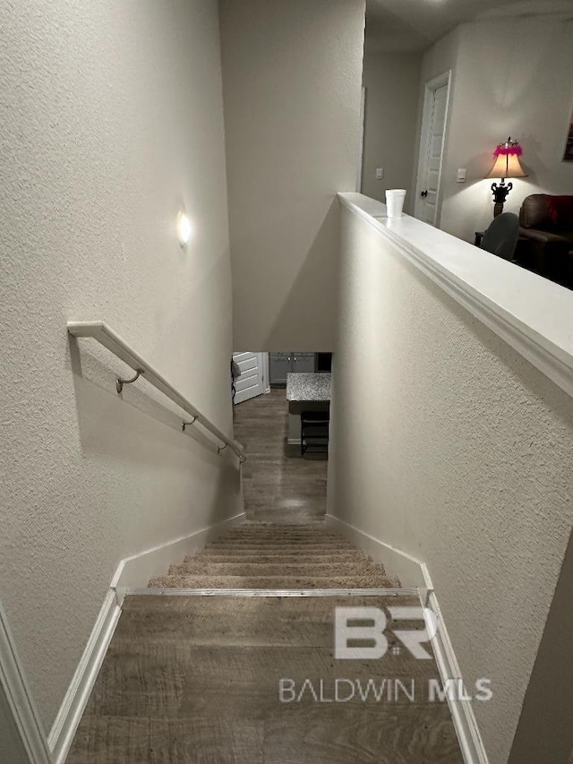 stairs featuring a textured wall and wood finished floors