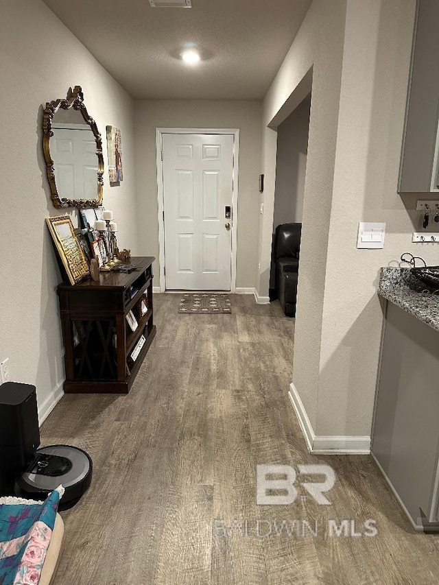 hall with dark wood-style flooring, visible vents, and baseboards