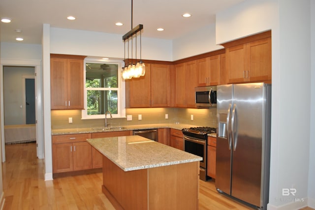 kitchen with light stone countertops, stainless steel appliances, sink, pendant lighting, and a center island