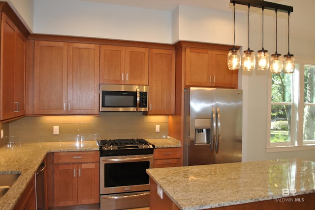 kitchen featuring tasteful backsplash, light stone countertops, stainless steel appliances, and decorative light fixtures