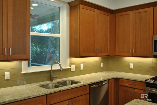 kitchen with light stone countertops, sink, appliances with stainless steel finishes, and tasteful backsplash