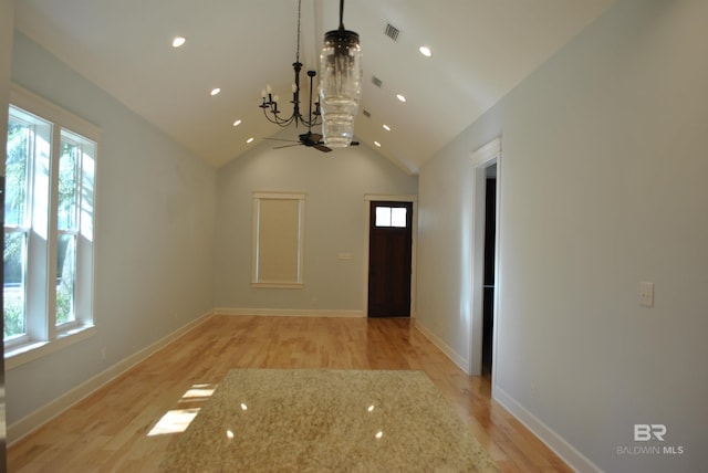 interior space featuring ceiling fan with notable chandelier, light hardwood / wood-style floors, and lofted ceiling