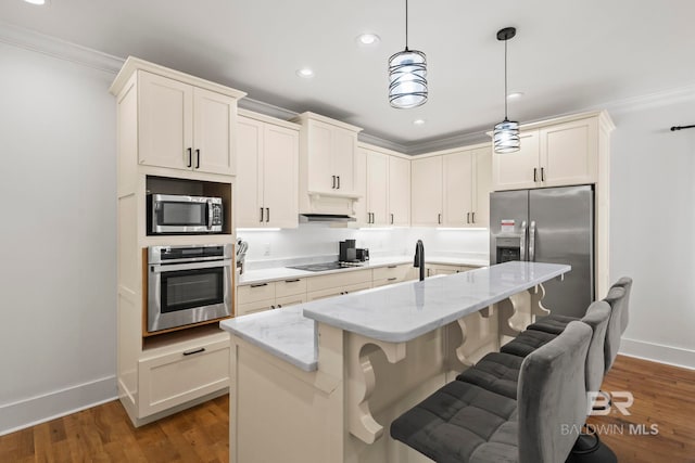 kitchen with a kitchen breakfast bar, light stone countertops, wood finished floors, and appliances with stainless steel finishes