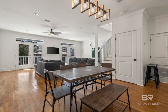 dining space with french doors, wood finished floors, crown molding, and stairway