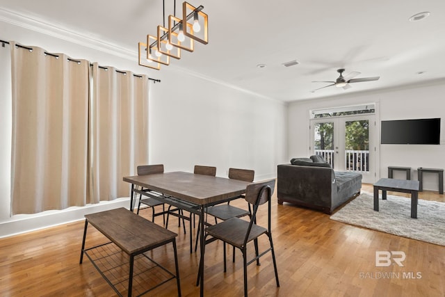 dining space with light wood-style flooring, french doors, visible vents, and ornamental molding