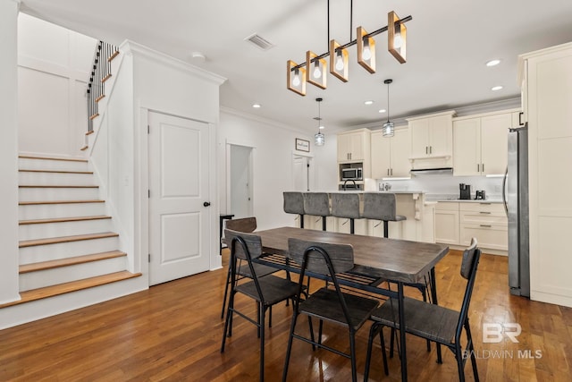 dining room featuring visible vents, dark wood-type flooring, stairs, ornamental molding, and recessed lighting